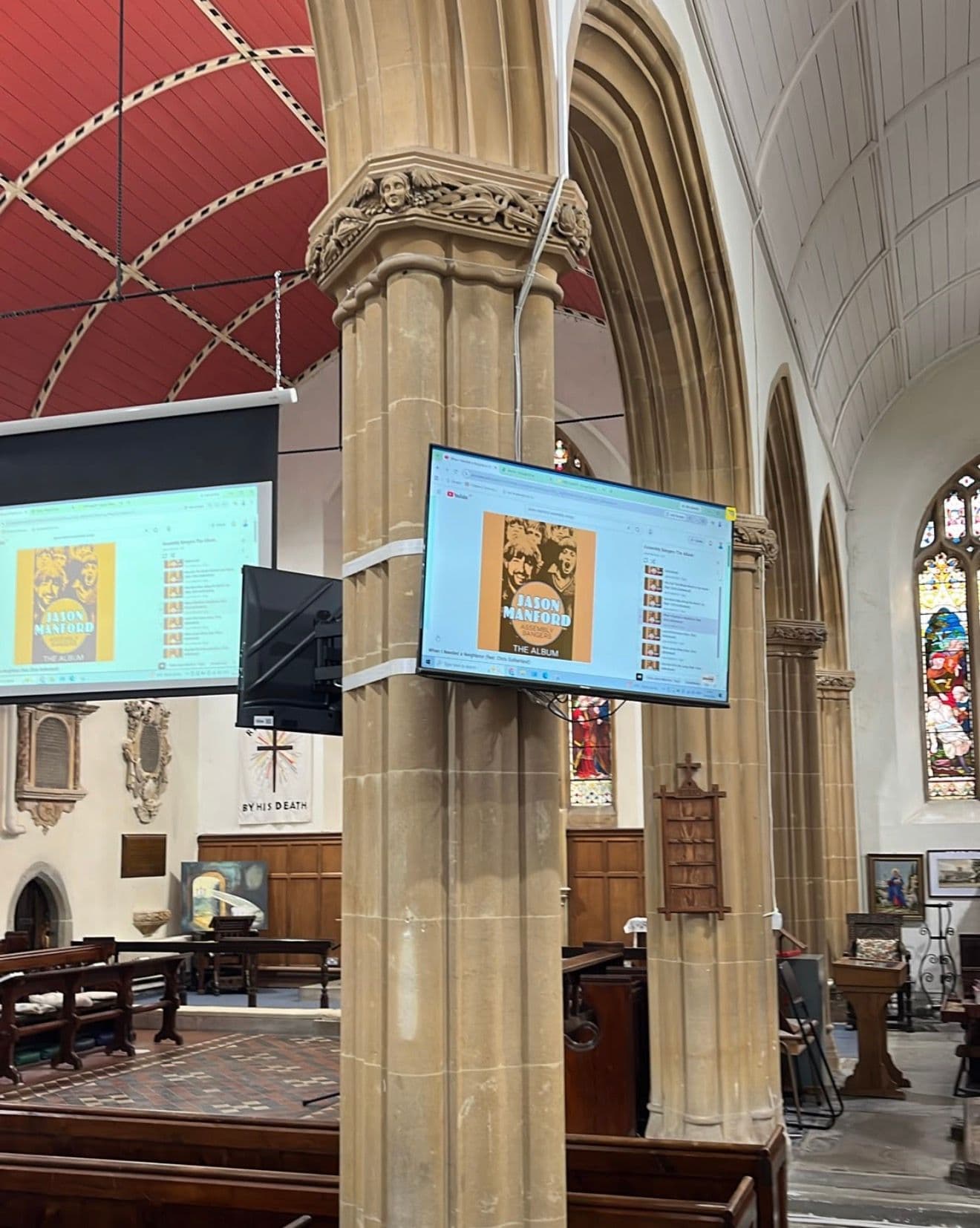 2x screens mounted on pillar in church